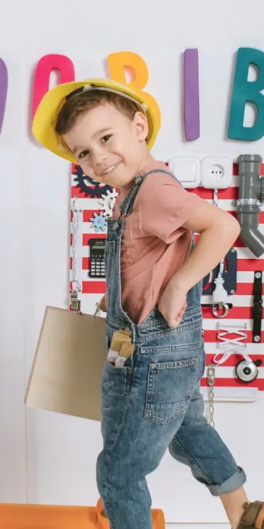 uśmiechnięty chłopiec trzymający w ręku drewnianą układankę